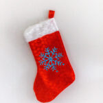 A red Christmas stocking with a blue snowflake sewn on it